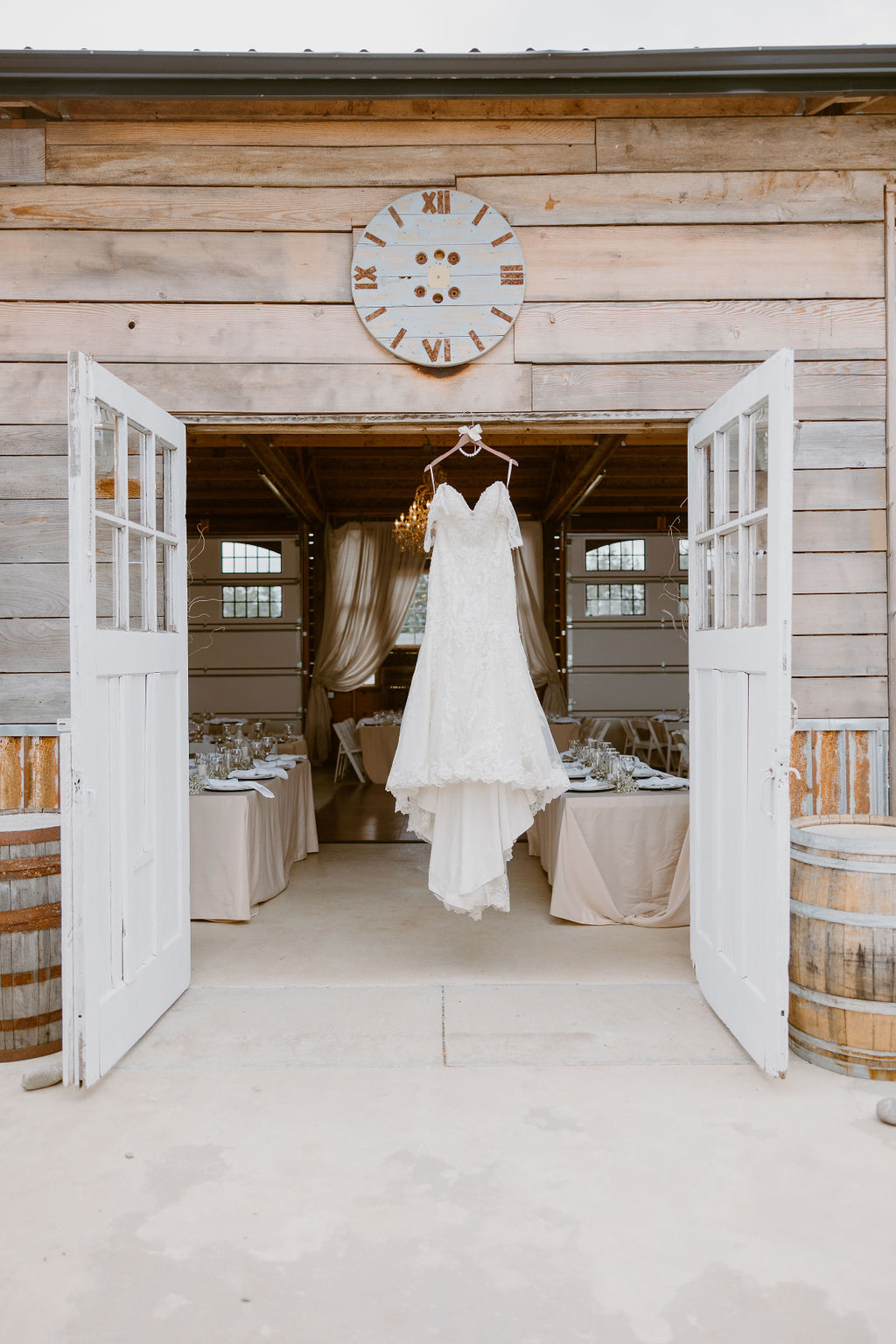 A wedding dress hangs from the rustic barn doors, ready for the ceremony.