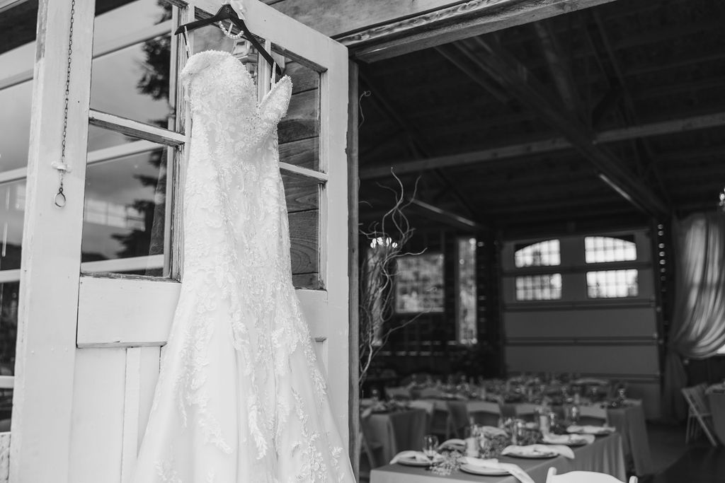 Close-up of a wedding dress hanging from a barn door, showcasing its intricate details.