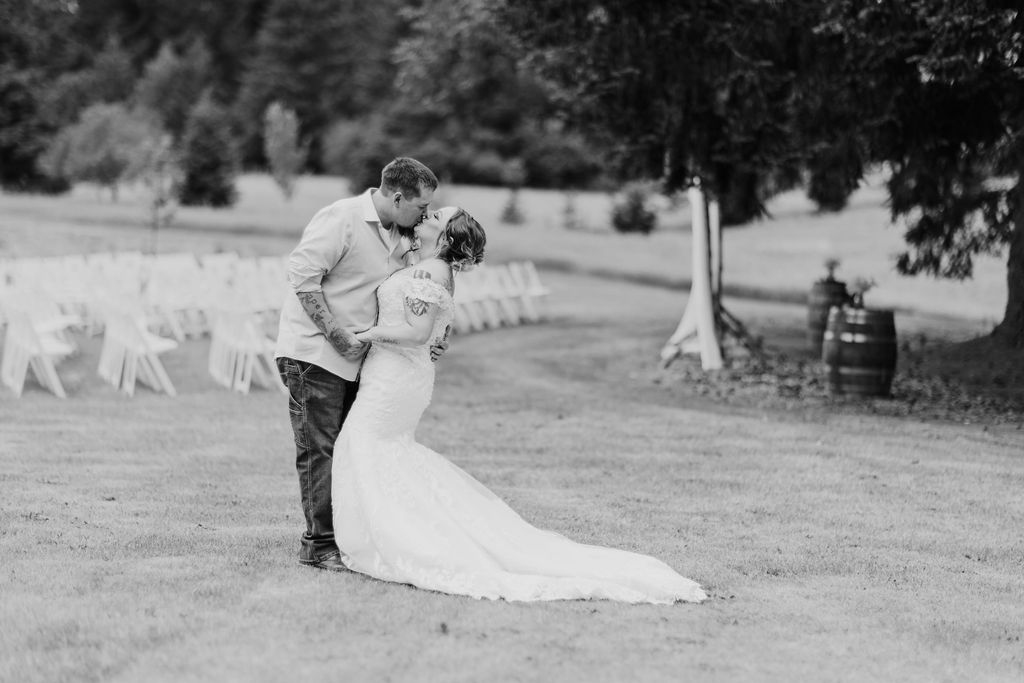 A bride and groom share a romantic kiss in the open fields, embracing the natural beauty of their wedding venue.