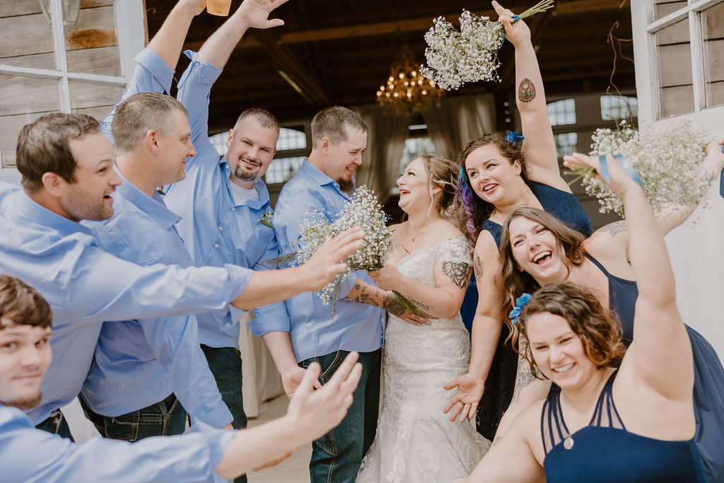 The wedding party surrounds the bride and groom with laughter and joy after the ceremony.