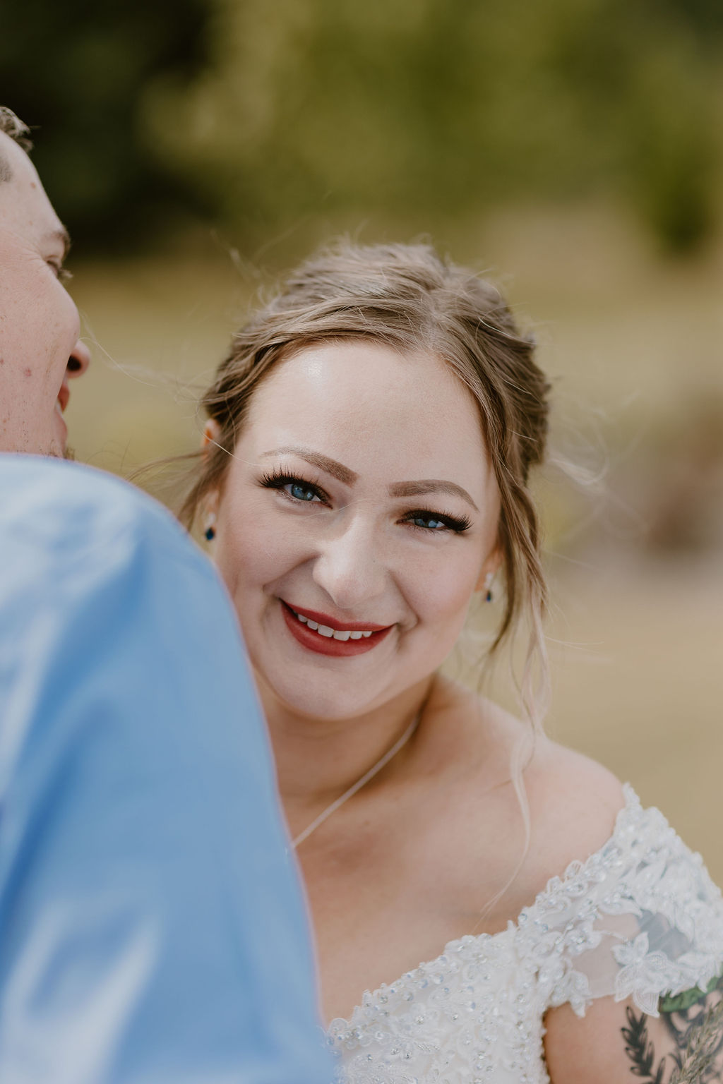 A close-up of the bride smiling warmly at the camera, highlighting her makeup and hairstyle.