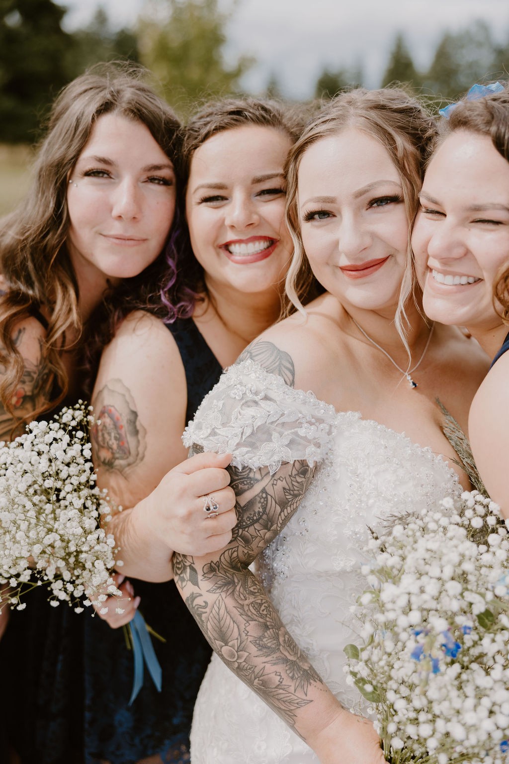 The bride and her bridesmaids share a joyful moment together, holding bouquets of flowers.