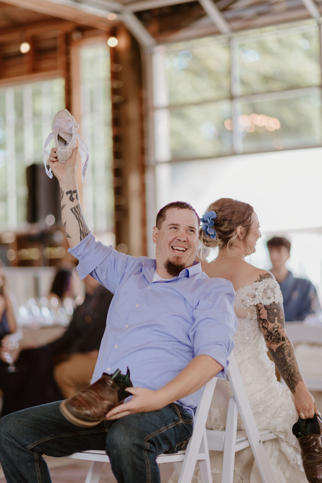 Groom holding up bride's shoe during the wedding shoe game.