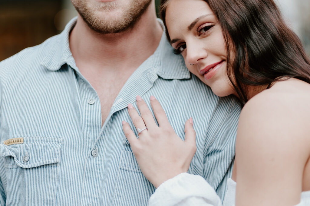 Close-up of Courtney’s hand resting on Brandon’s chest, showing her engagement ring.