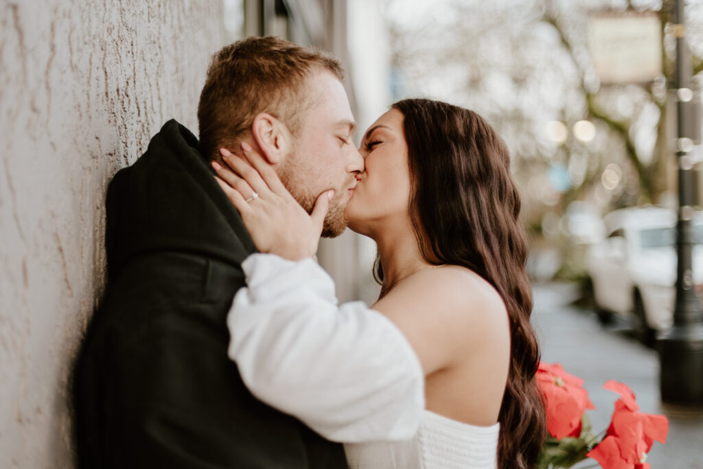Brandon and Courtney sharing a kiss against a wall in downtown Camas.