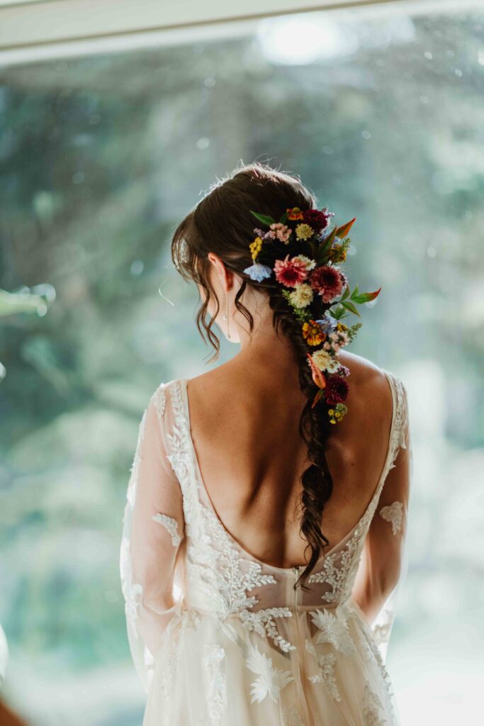 Close-up detail shot of the brides hairstyle with fresh colorful wildflowers decorating her braid