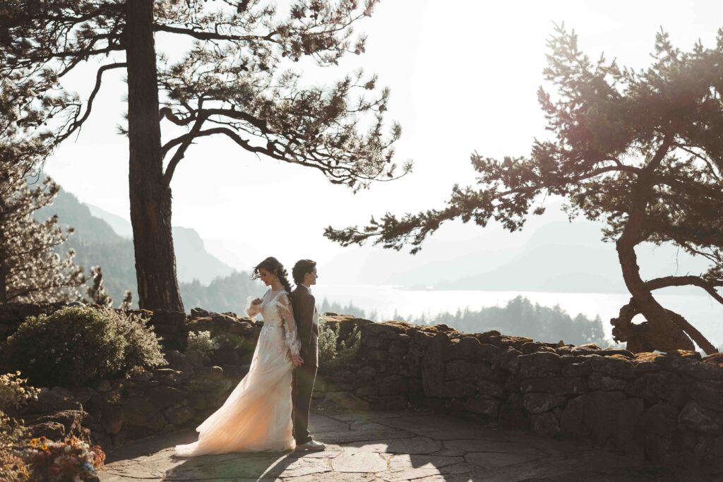 Wide shot of LGBT brides standing back to back during their first look during their Columbia River Gorge elopement in Hood River, Oregon