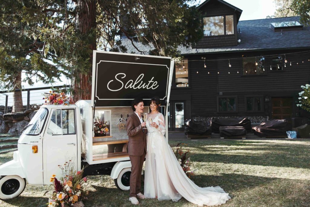 Two brides share a toast in front of their classic european bar cart at the Griffin House in Hood River, Oregon