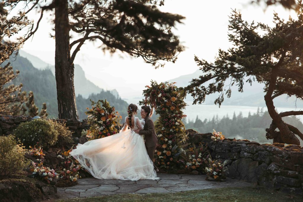 A bride swishes her wedding dress around as she laughs with her partner in Hood River, Oregon