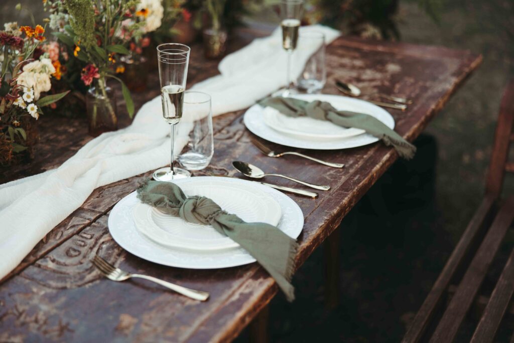 table setting details with plates, sivlerware, and champagne glasses on a wood table