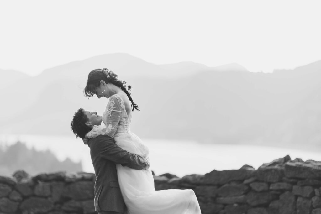 black and white photo of two brides holding each other while they spin in front of mountains at the Griffin House in Hood River, Oregon