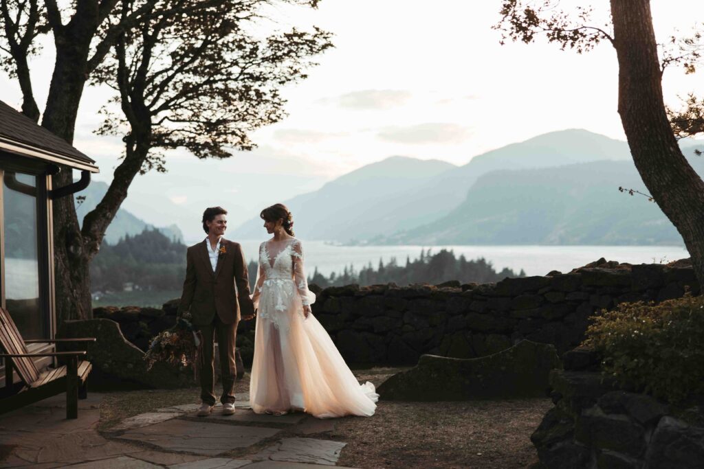 Two brides holding hands while they walk away from the sunset in the Columbia River Gorge