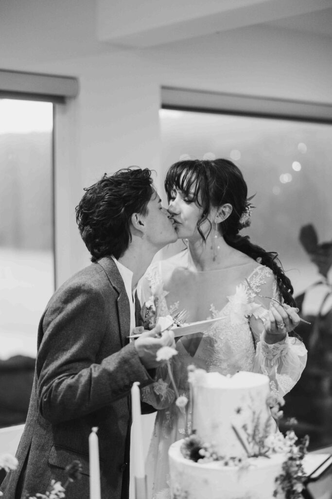 two brides kiss as they cut their cake at their wedding reception at the Griffin House in Hood River Oregon