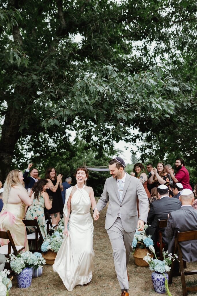 Bride and groom walking through forested wedding venue in the Pacific Northwest