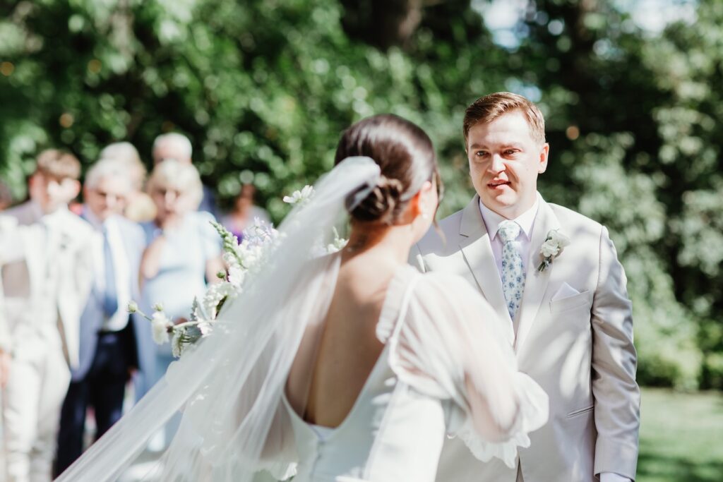 a groom gets his first look at his bride coming down the isle during their hot summer wedding day