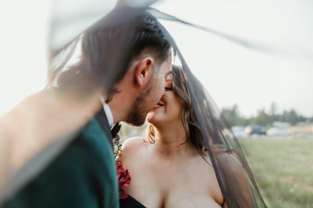 a bride and groom kiss under her black veil at sunset in vancouver wa