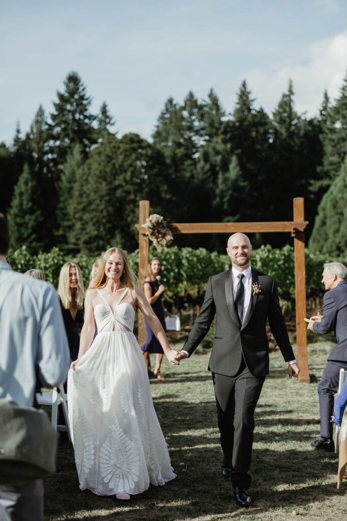 bride and groom hold hands as they walk together back down the isle on their wedding day