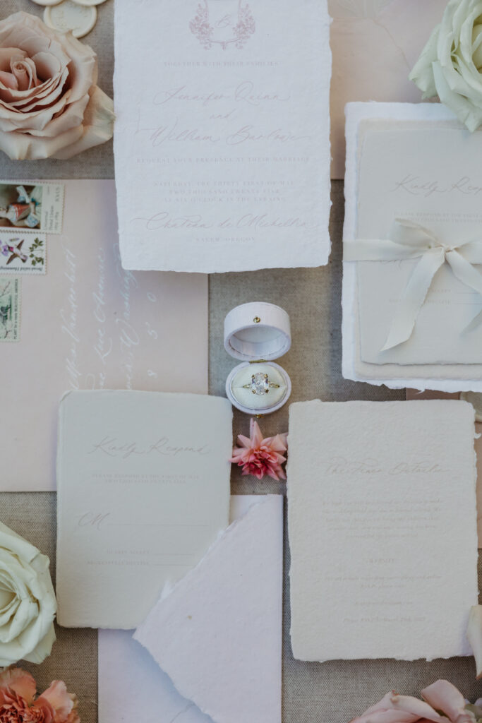 wedding ring and wedding plans photographed with invitations and roses in the Pacific Northwest