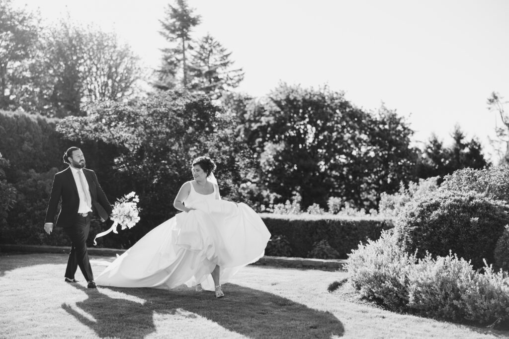 bride and groom walk together through a lush green garden during their summer wedding day near Vancouver WA
