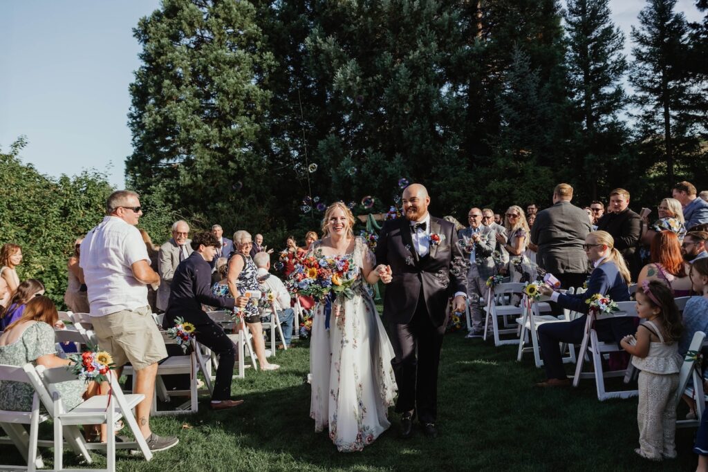a bride and groom celebrate as they head back down the isle at Mcmenamins Edgefield during their summer wedding day