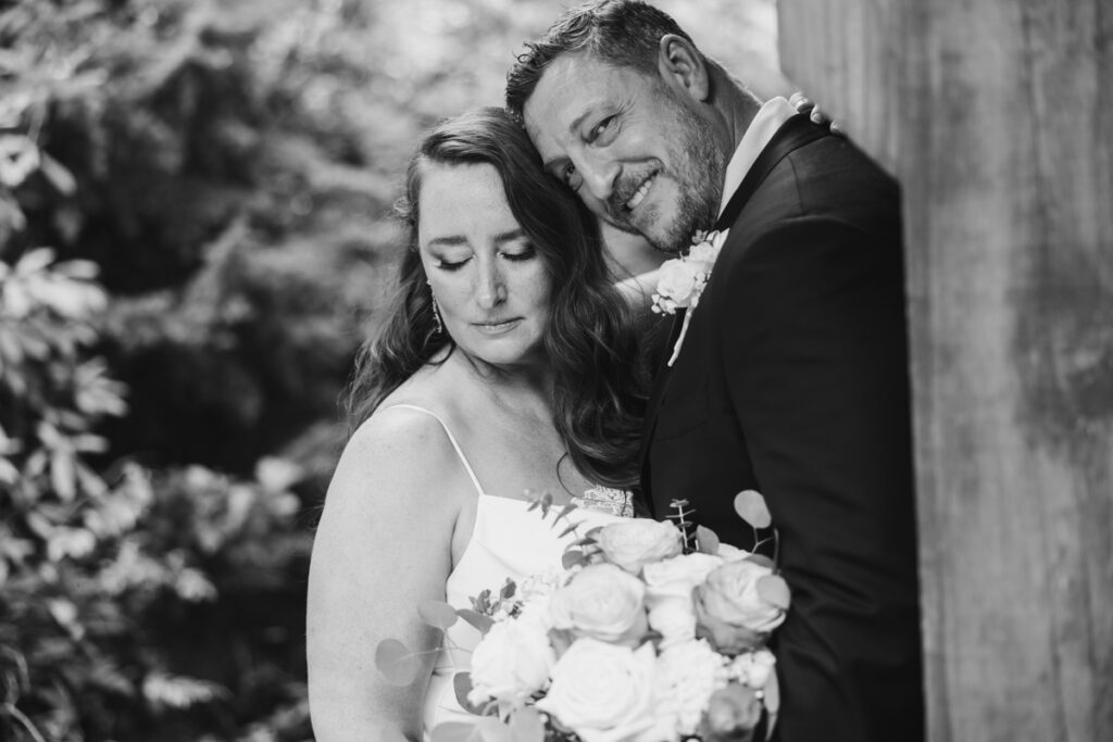 black and white bridal portrait of bride and smiling groom at Summit Grove Lodge in Ridgefield WA taken by Vancouver Washington Wedding Photographer