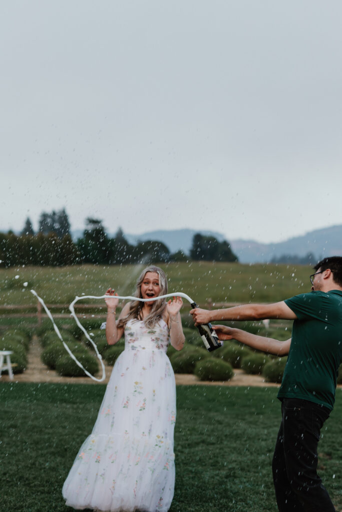 Olivia and Quinton popping champagne in blooming lavender fields at Hood River Lavender Farms — Hood River engagement photographer
