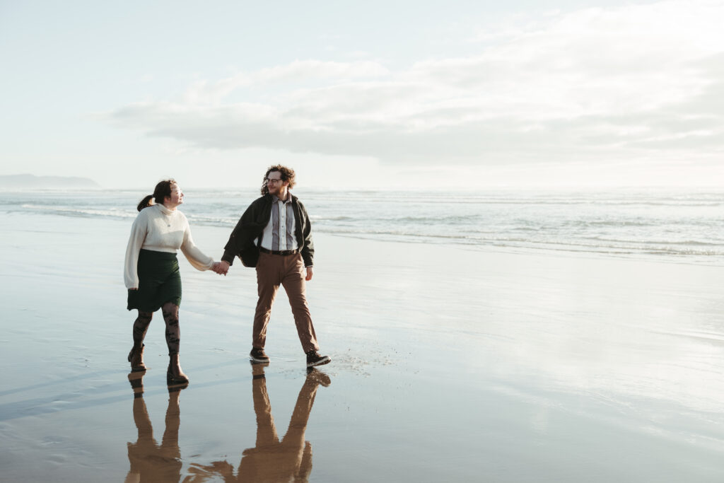 Couple walking along the beach near the Peter Iredale wreck Fort Stevens State Park Oregon