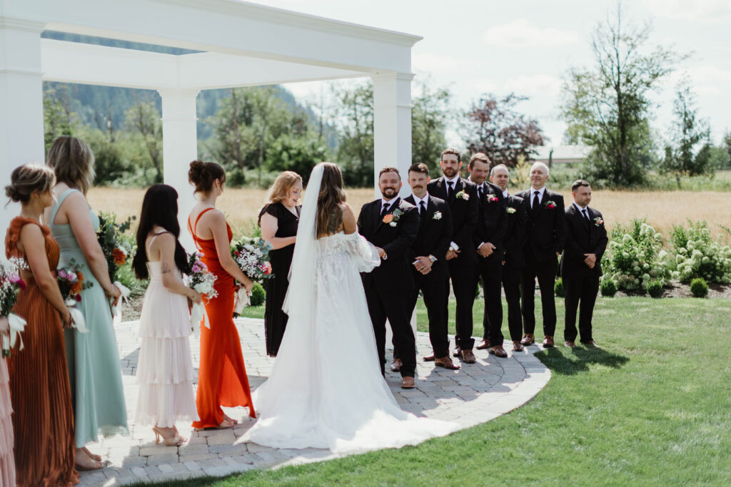 Couple exchanging vows under white archway at Mount Peak Farm outdoor ceremony Enumclaw Washington