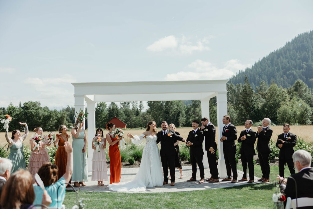 Couple's first kiss at outdoor ceremony under floral archway at Mount Peak Farm Enumclaw Washington