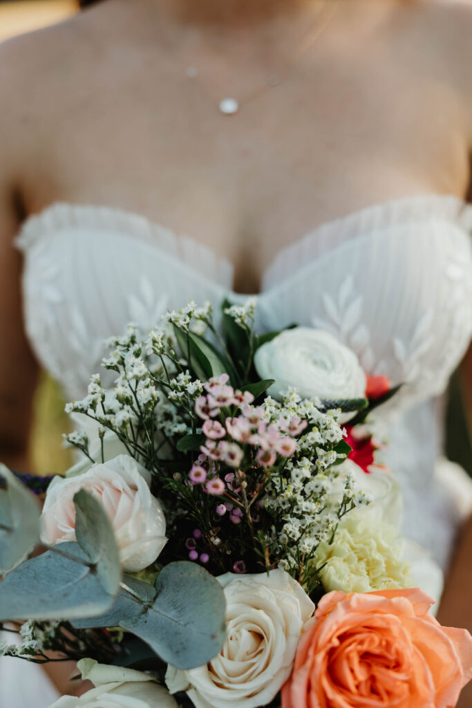 Close up of white wedding dress and wildflower bouquet at Mount Peak Farm