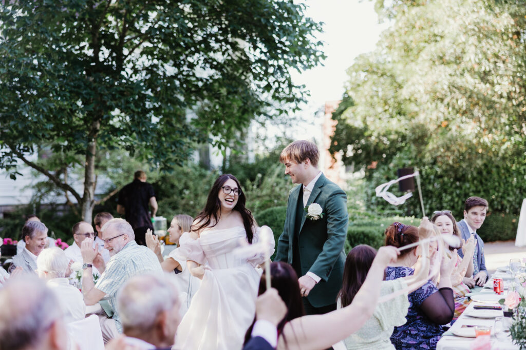 Bride and groom entering their reception to a cheering crowd