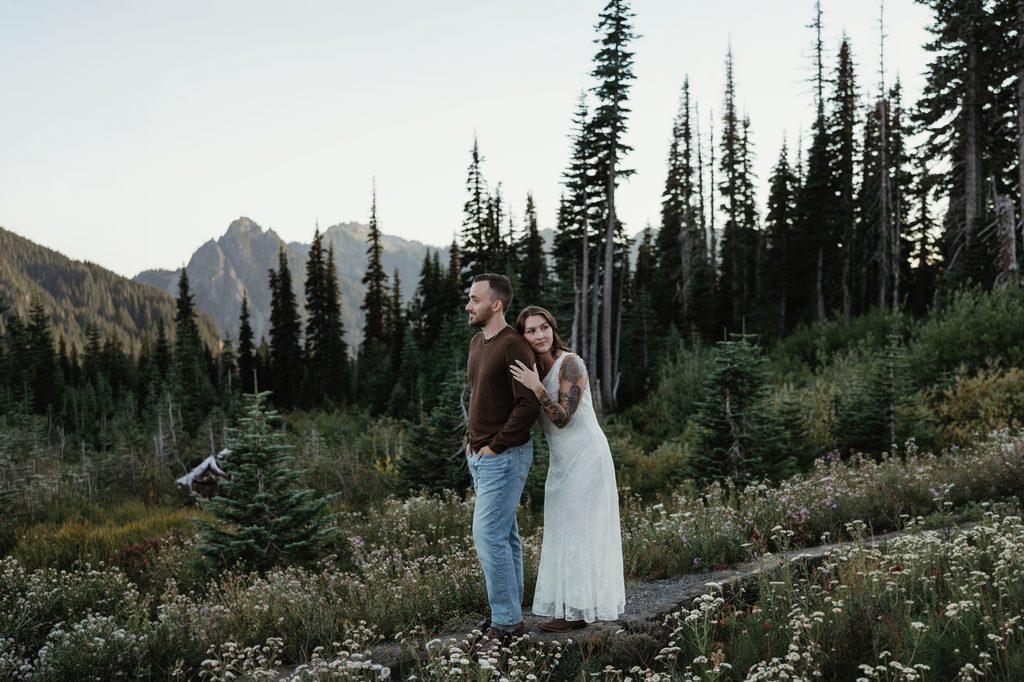 Holding each other in sweeping evergreen trees and wildflowers