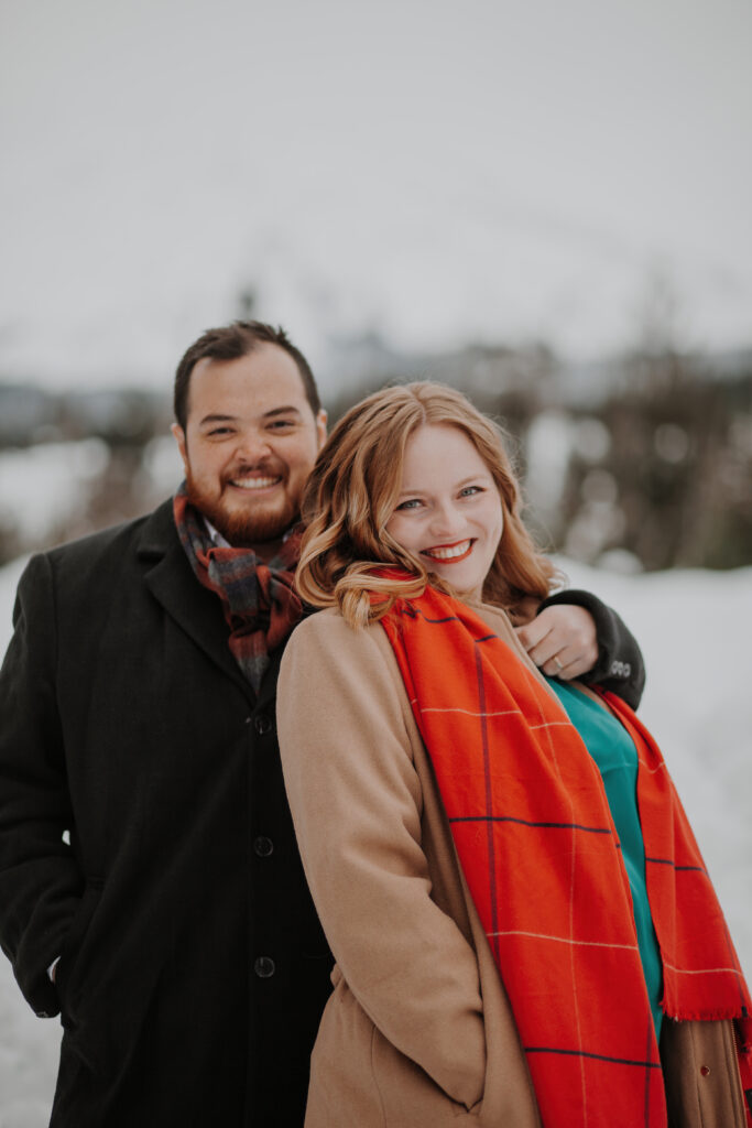 all smiles at the camera while they are bundled up in the snow at mt. st. helens for their engagement photos